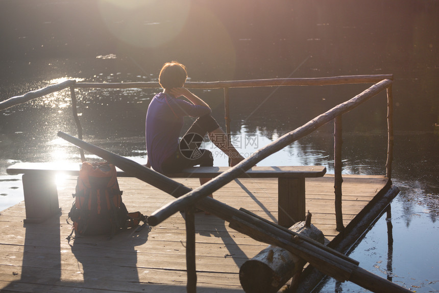 山湖女游客在日落时坐码头上图片