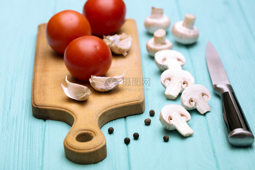 西红柿蘑菇大蒜蓝背景的剪切板上大蒜图片