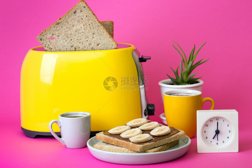 黄面包机和一杯粉红背景的咖啡图片