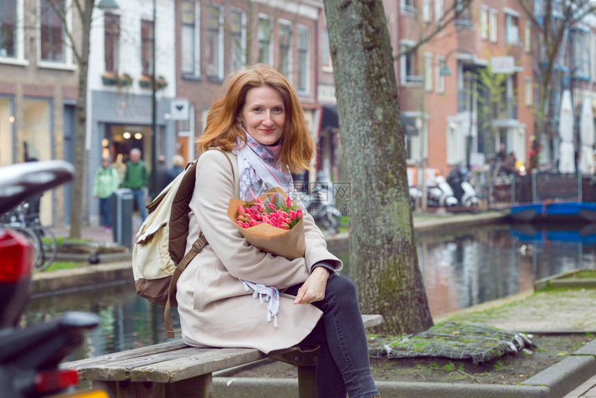 女孩拿着一束郁金香坐在阿姆斯特丹的长椅上图片