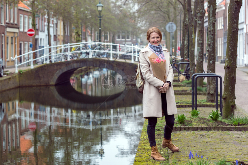 女孩拿着一束郁金香站在阿姆斯特丹街上图片