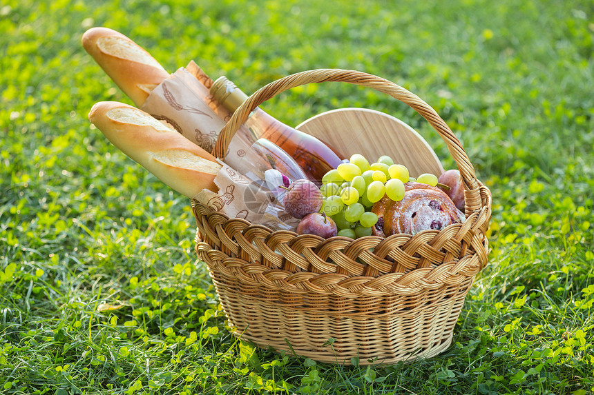 夏季在草地上野餐面包葡萄眼镜和卷子放在绿草上图片