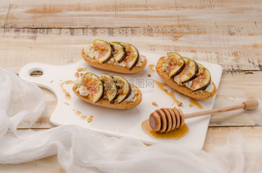 餐板上带有无花果奶酪迷迭香蜂蜜和胡桃的瑞典吐司图片
