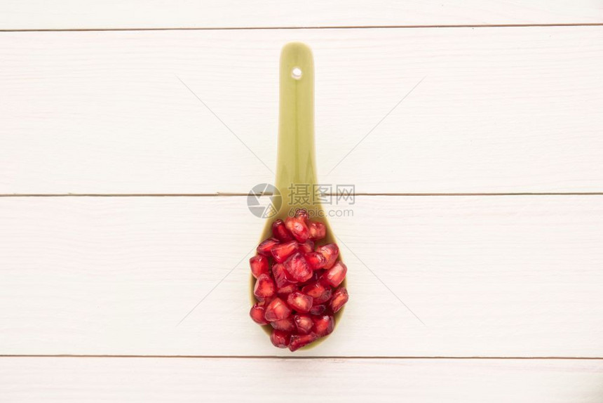 陶瓷勺上红熟的石榴种子生锈木板背景顶视图复制空间图片