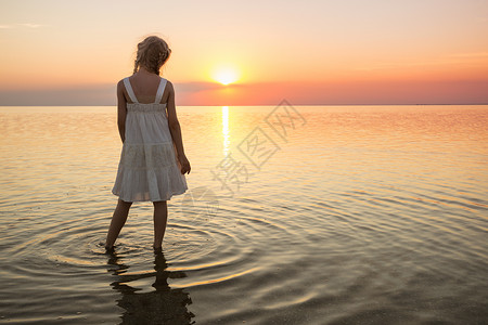 在海边快乐的周末小女孩看着海边的日落图片
