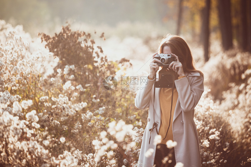 古老的秋天女孩与古老的摄像头在日落时走田野中图片