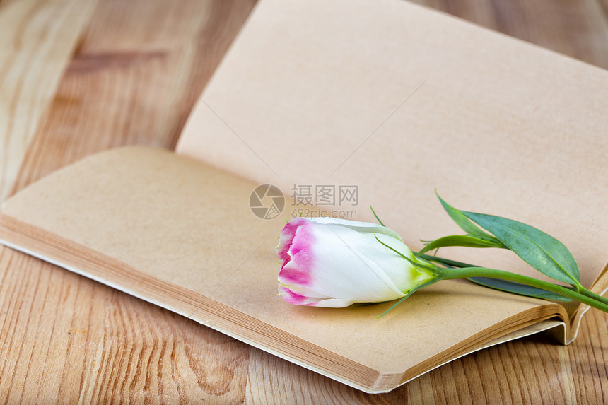 笔记本和木制桌上的鲜花图片