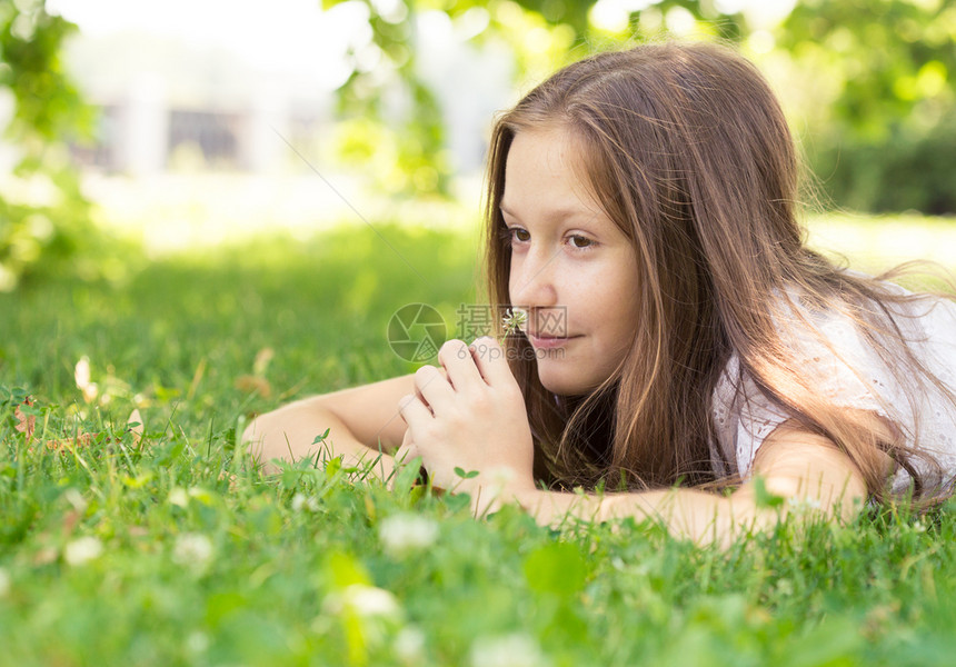 女孩躺在草地上拿着花朵图片