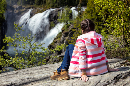坐在岩石上看瀑布的女孩高清图片