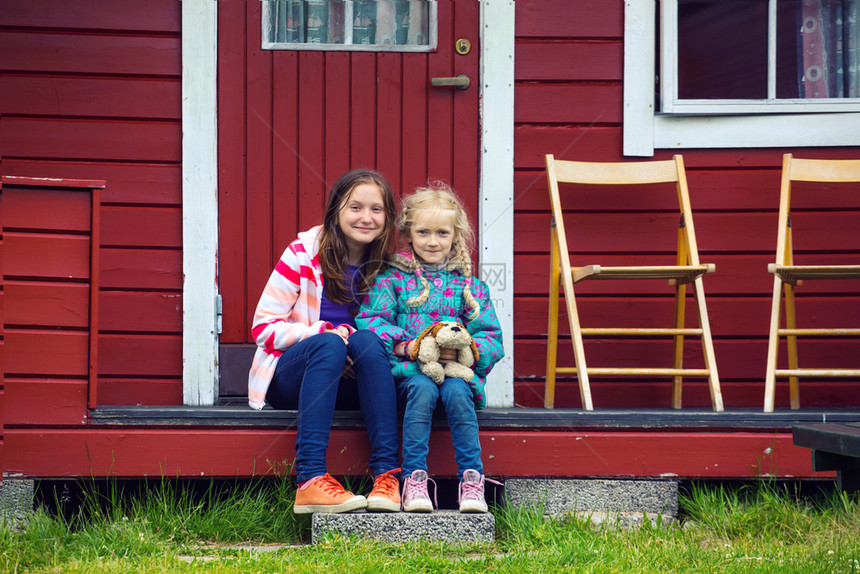 坐在营地附近的红房子姐妹女孩Norway图片