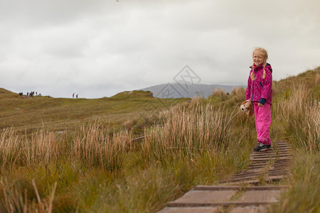 微笑的小女孩沿着足迹走在诺维吉亚山脉丘陵诺威图片