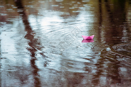 雨中水坑的粉红色纸船图片