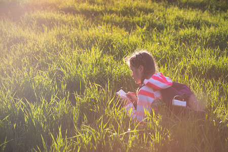 女孩徒步旅行者坐在草上享受日落图片