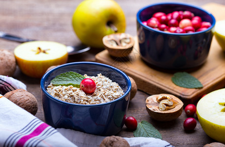 健康早餐燕麦红莓坚果木制桌上的苹果图片