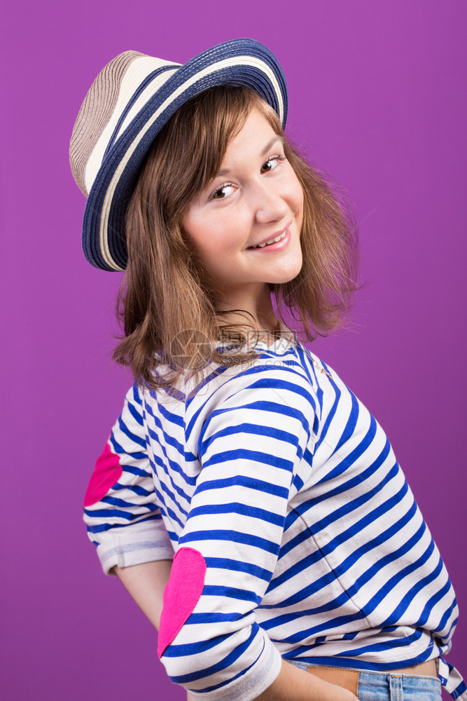 美丽的笑着少女戴帽子假扮紫色背景图片