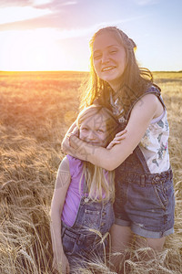 假期微笑的快乐女孩姐妹在麦田上图片