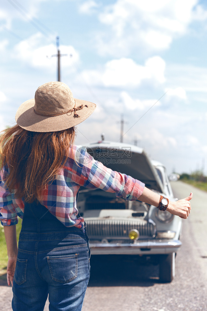 在田野路上搭便车的年轻妇女图片