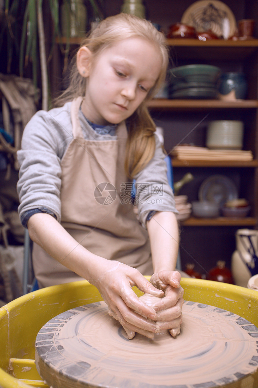 陶瓷车间女孩在陶瓷器和轮子上制造一锅粘土图片