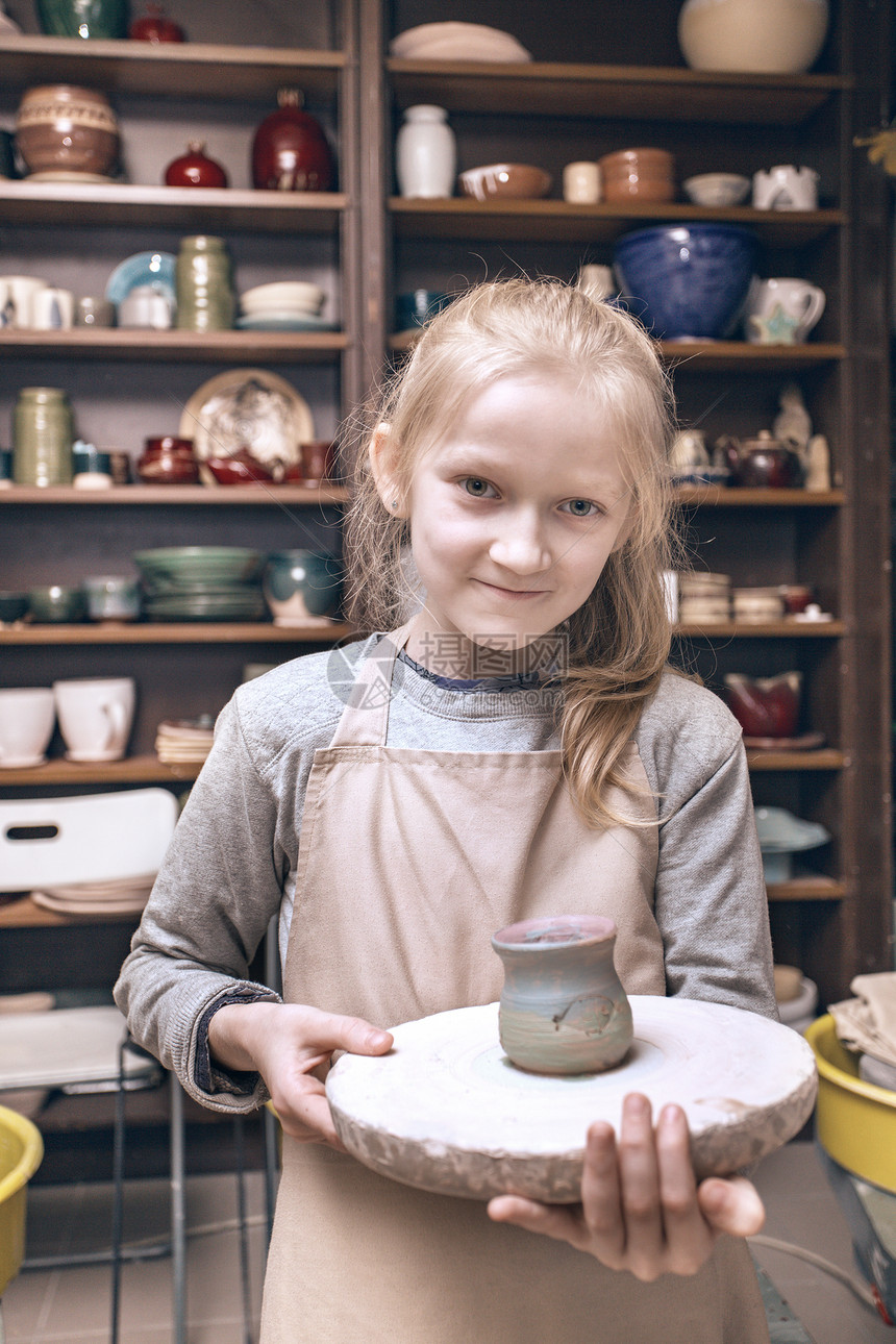 陶瓷车间快乐笑的小女孩做陶土锅图片