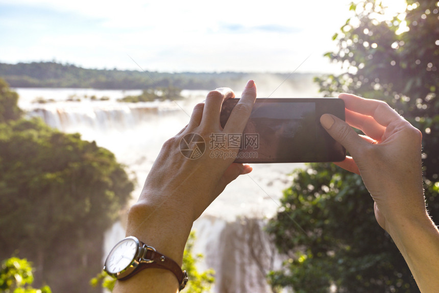 女孩用手机拍摄I瀑布的照片图片