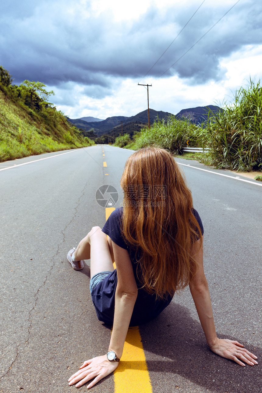 在阳光明媚的阴云天空荡的巴西路上女孩图片