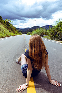 在阳光明媚的阴云天空荡的巴西路上女孩图片