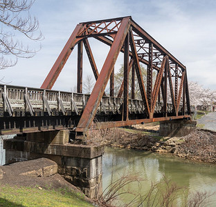 石家庄铁道大学在摩根镇旧的钢环桥载有步行和骑自车的通道穿过甲板小溪有樱花钢环桥载有在甲板小溪上行走的自车背景