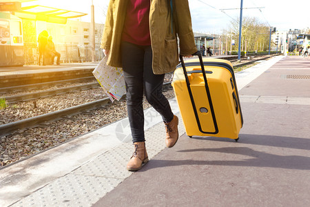 带着背包和黄色大手提箱的游客女孩站在平台上等待火车高清图片