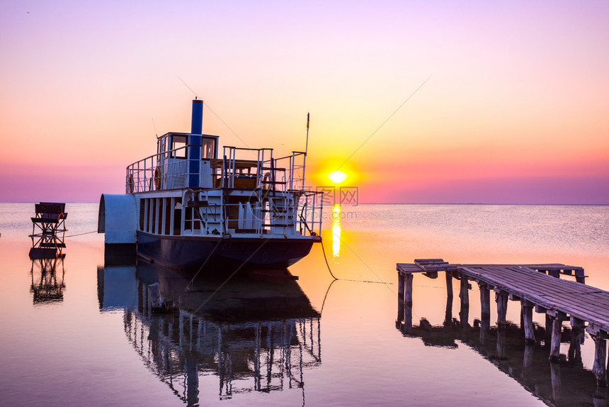 在日落时以船和码头在前方的海景图片