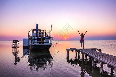 太阳码在海船和日落背景的码头上女孩背景