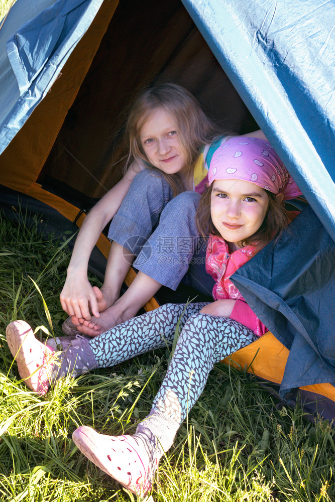 坐在帐篷旁边的笑着女孩徒步旅行者图片