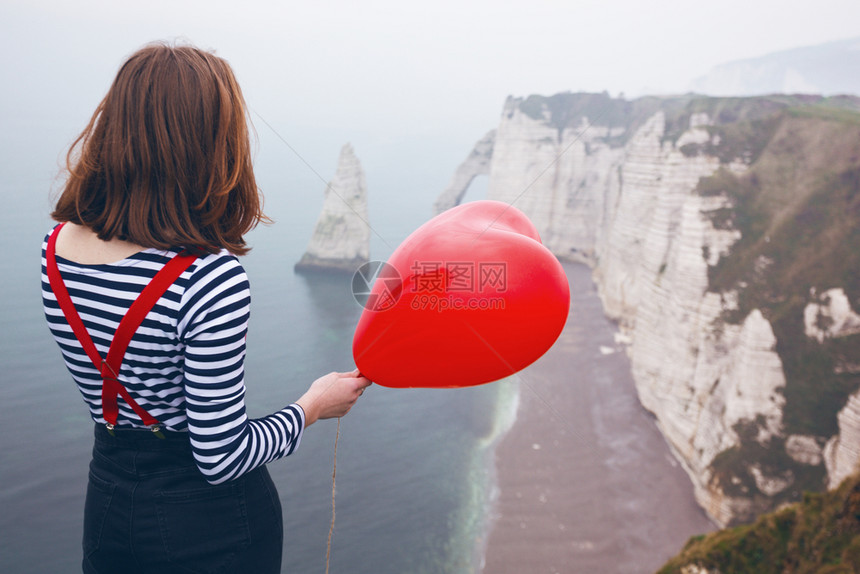 笑着的女孩带红气球以心脏的形状在风景礼仪的背图片