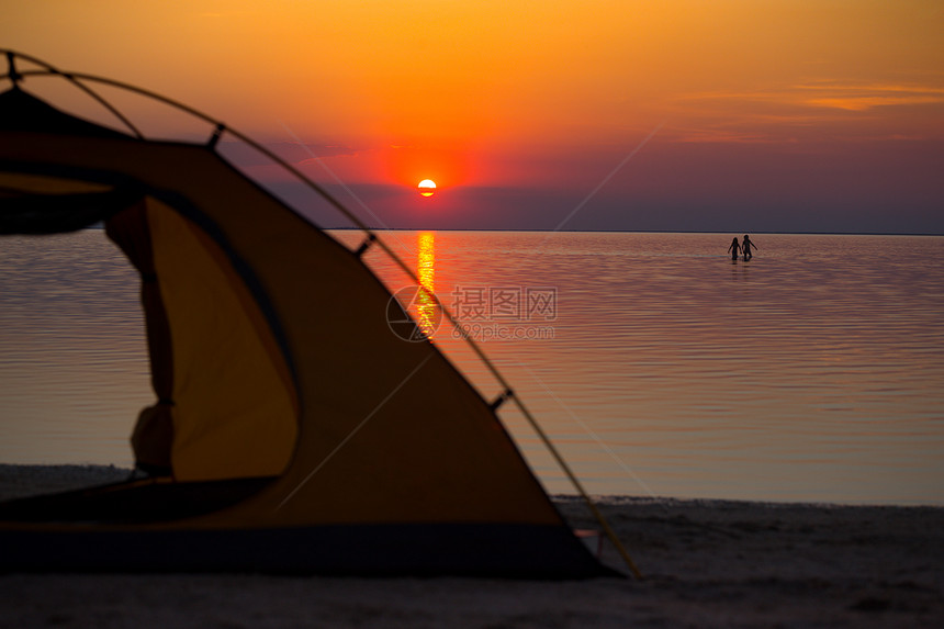 日落背景的帐篷和在海上行走的孩子们轮廓图片