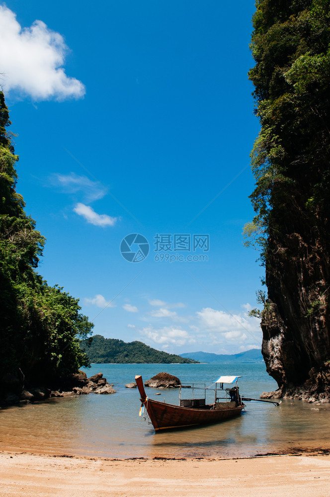 在海滩上KohlantKrbiThlnd附近的KohTalbeng海边悬崖的KohTalbeng海边Krabi和Th木制长尾小艇图片