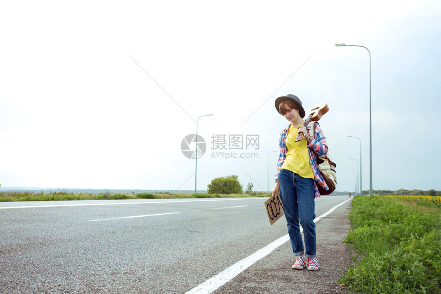 年轻女孩带着吉他沿路走来搭便车图片