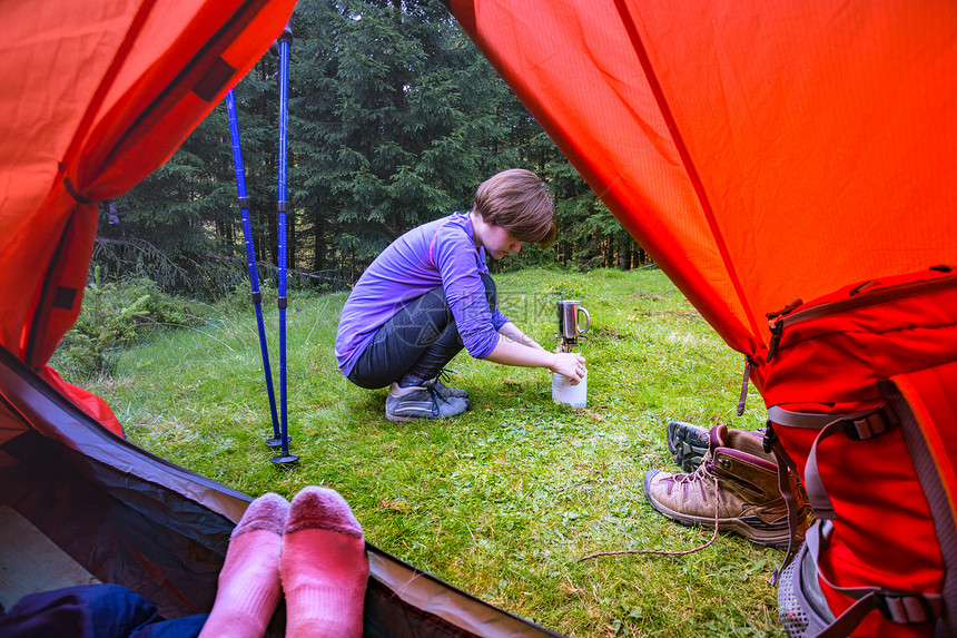 观光客女孩在帐篷里用燃烧器做饭图片