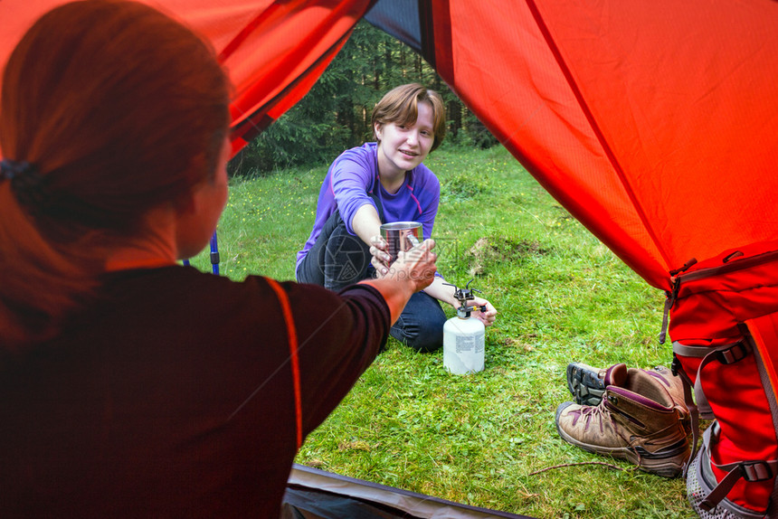 观光客女孩在帐篷里用燃烧器做饭图片