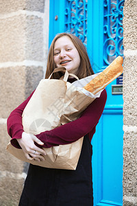 微笑着的法国女孩在城市的街边带着面包圈图片