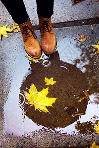 在雨季穿皮靴踩水坑的女孩背景图片