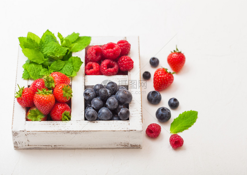 餐桌背景的白木箱中新鲜有机果子草莓蓝和薄荷叶图片