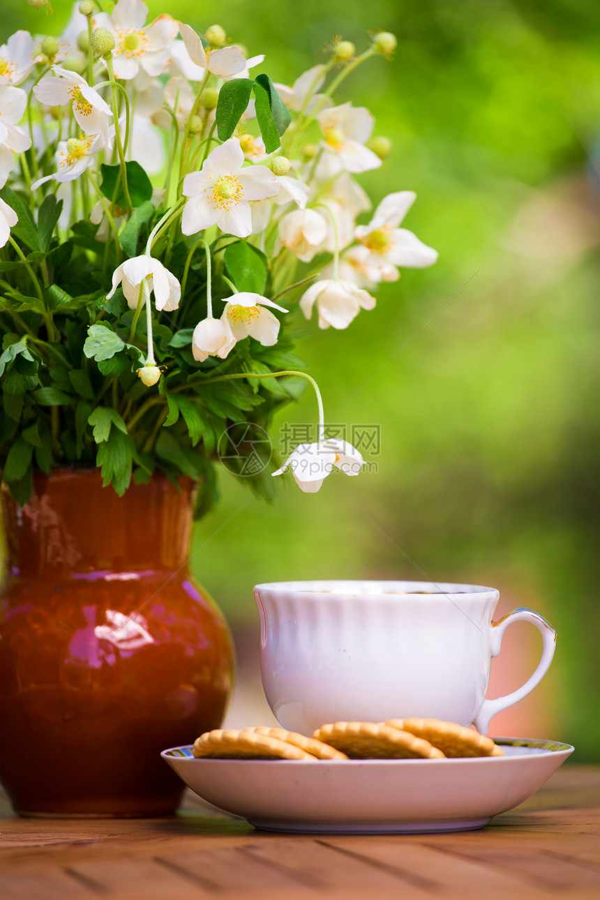 在园圃的木制桌边有茶杯和安悦图片