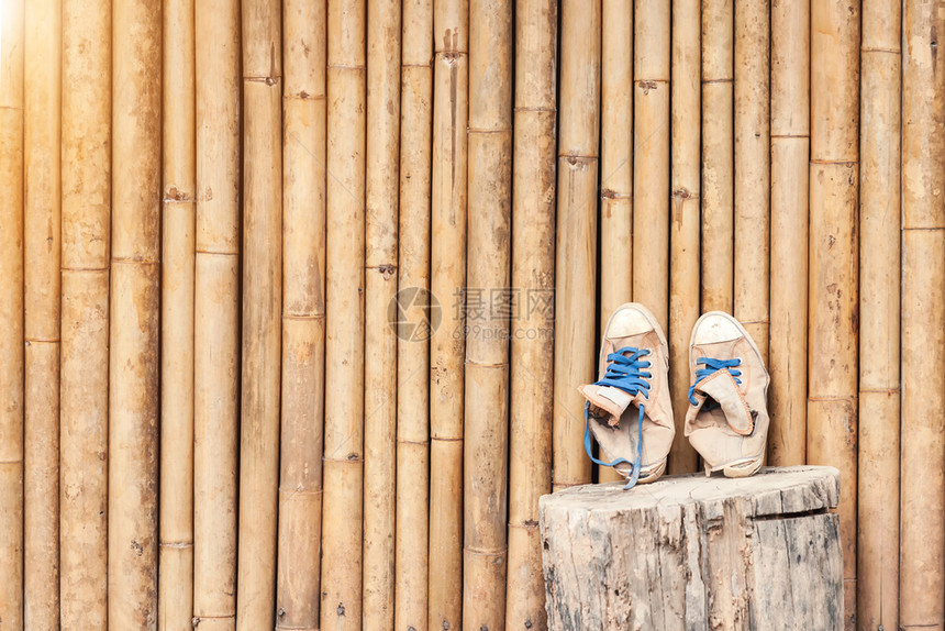 一对老式经典运动鞋靠在竹墙上旅行概念背景图片