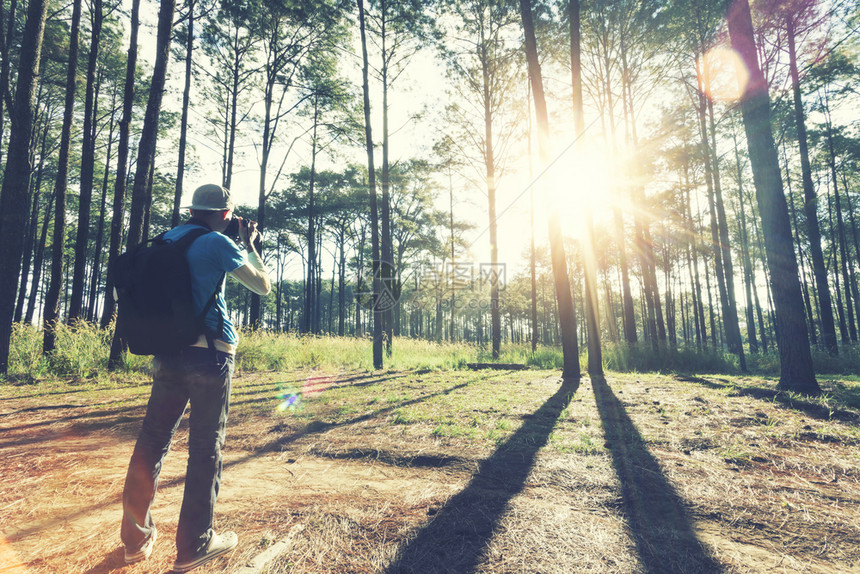 旅行者在森林里拍照早上阳光耀希望有灯光旅行和假期的概念图片