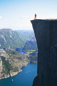 女孩远足者站在前方看着山上在挪威边的著名悬崖上高清图片
