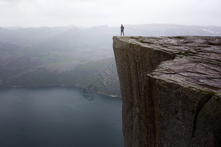 乔雅登玻尿酸快乐的女童徒步旅行者站在前方看着高在上的日子山峰在挪威边的有名悬崖上背景