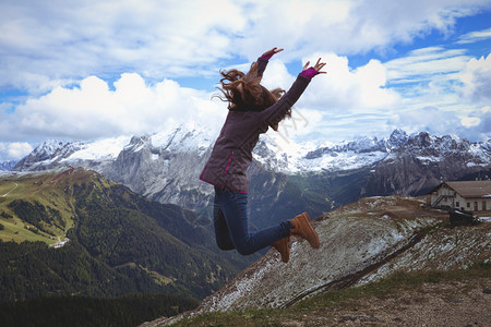 女孩徒步旅行者在山上跳花朵意大利图片