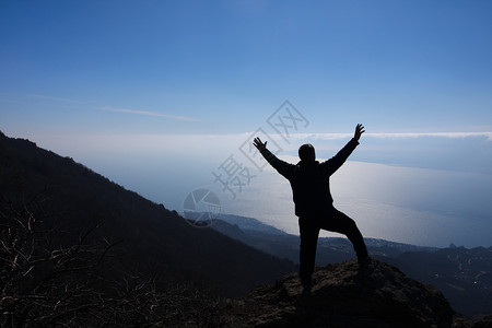 男人徒步旅行站在岩石上仰望天空图片