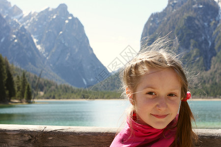 在阳光明媚的日子带着山湖背景的微笑小女孩肖像图片