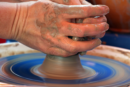 人手在陶匠的车轮上用粘土塑造图片