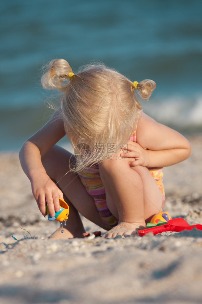 小女孩在海滩上带着玩具欢乐图片